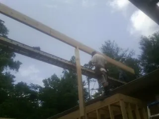 Carpenter setting a ridge beam over a new addition frame — Ice Dam Removal by Roofing Brothers in Sharon Springs