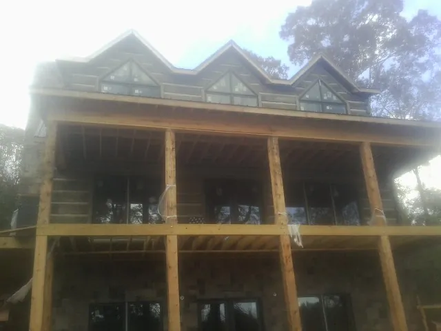 Dormers and porch framing on a large log home under construction — Roof Coating work by our crew in Sharon Springs