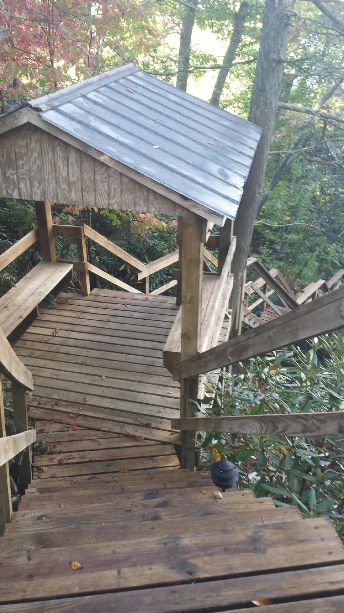Metal roofed shelter over wooden steps on a wooded walkway — Skylight Repair & Installation work by our crew in Sharon Springs