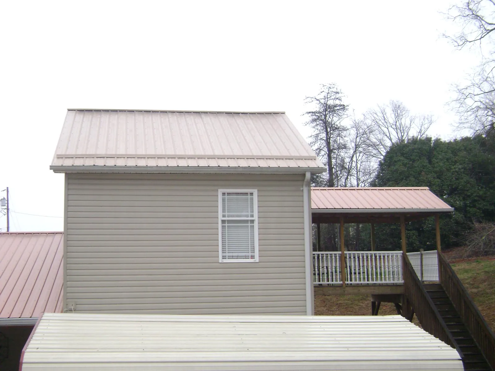 Tan metal roofs on a two story addition and attached porch, from a Roof Replacement job in Sharon Springs